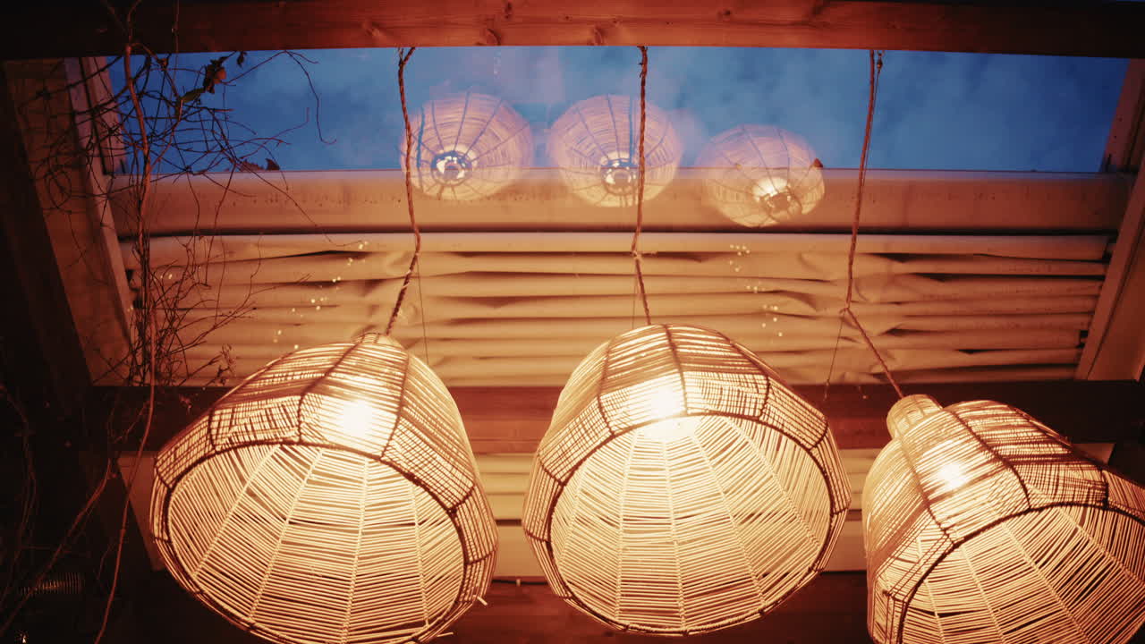 Lampu rotan dekoratif yang digantung di dalam ruangan dengan cahaya hangat dengan suasana interior yang nyaman dan bergaya