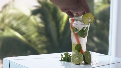 man-adjusts-lime-slice-on-glass-edge-with-wojito-cocktail