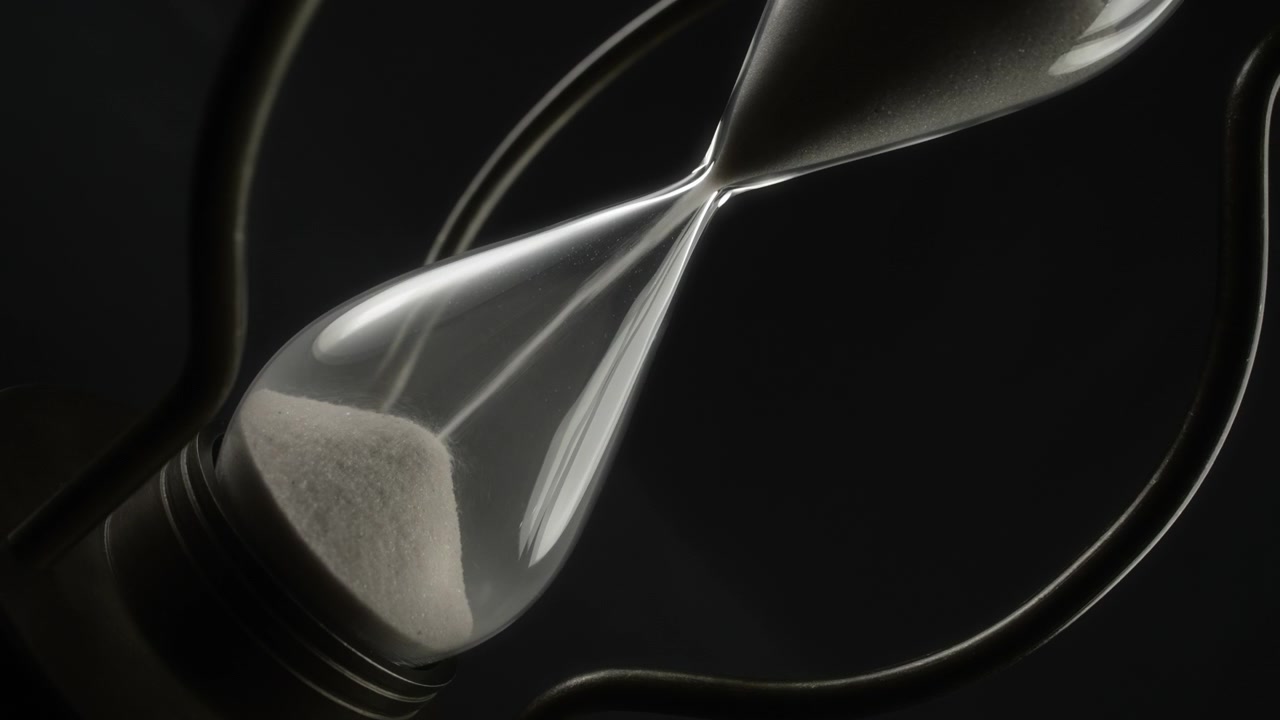 Sand Flowing Through a Vintage Hourglass on a Dark Background