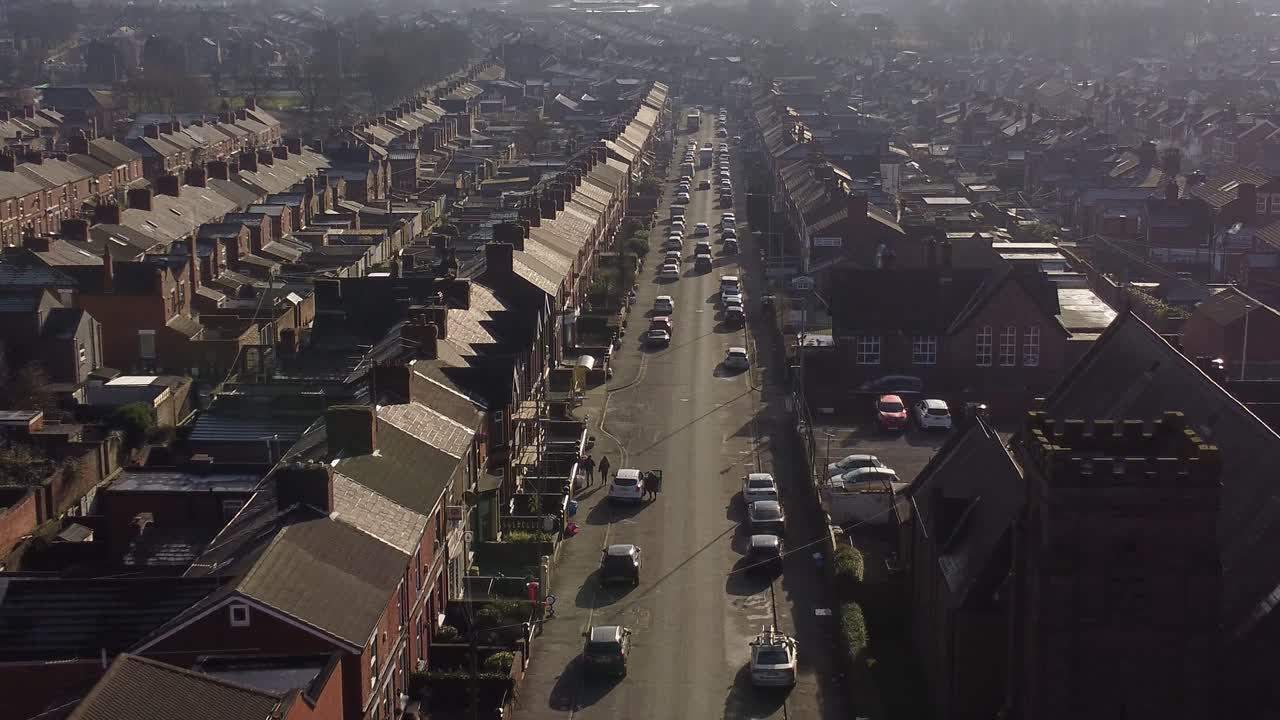 해가 뜰 때 분주한 시내 중심가로 이어지는 긴 도로가 있는 빅토리아 시대의 계단식 주택이 줄지어 있는 공중 상승 전망