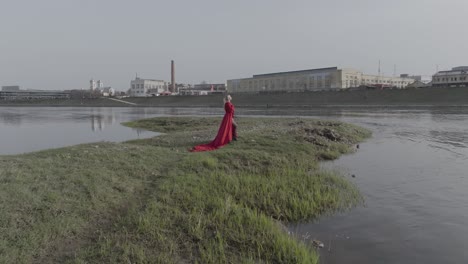 Toma-Aérea-Acercándose-A-Una-Modelo-Con-Un-Vestido-Rojo-En-Una-Pequeña-Isla