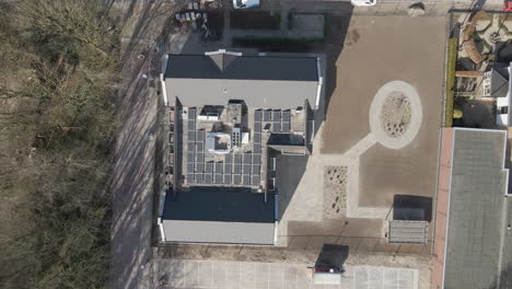 Top-down-aerial-of-solar-panels-on-top-of-large-elderly-home---drone-setting-down