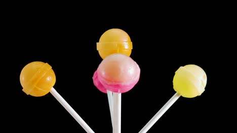piruletas en un fondo negro. el caramelo está girando en un palo. fondo de dulces