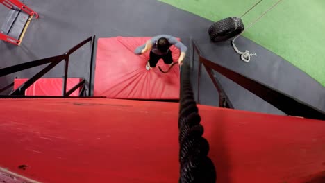 man performing rope climb exercise in fitness gym 4k