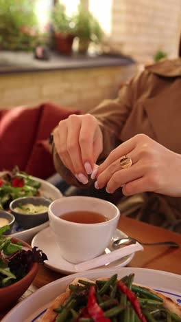 woman adding sugar to tea in a cafe