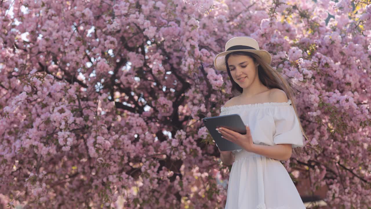 Woman with tablet in cherry blossom trees