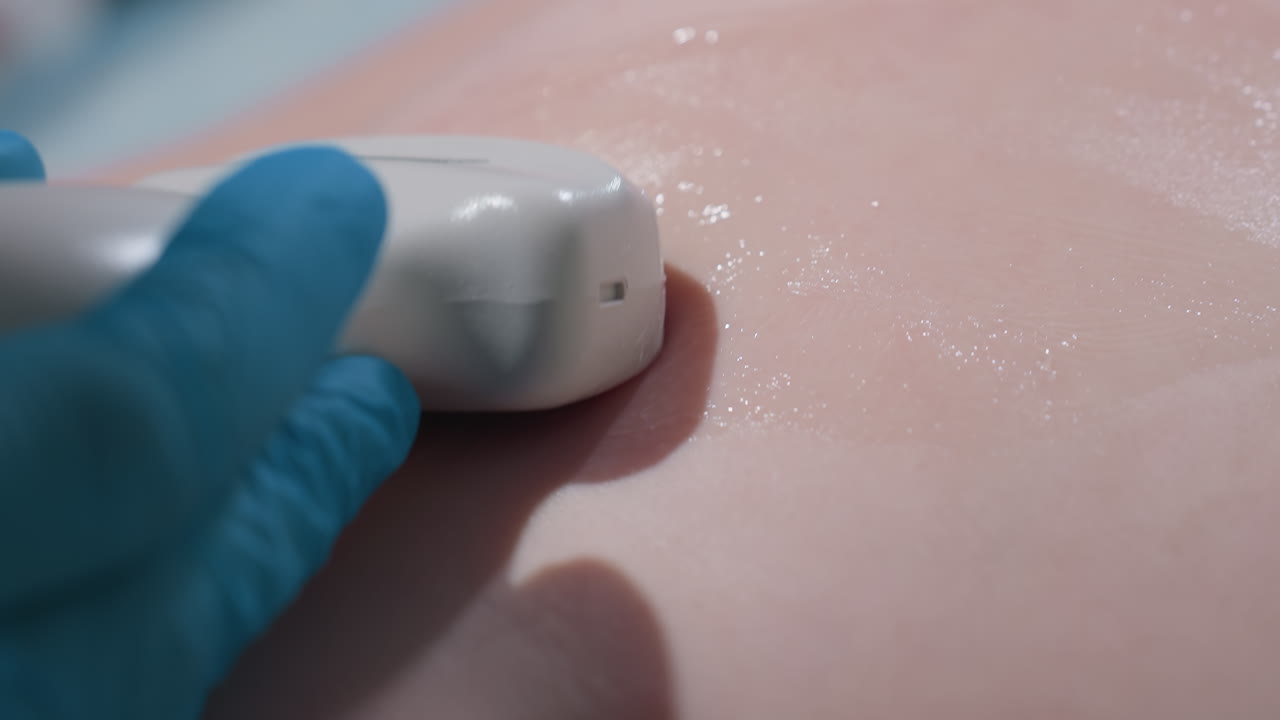 female doctor wearing lab gloves glides ultrasound probe over patient's skin covered in gel during medical examination, focusing on precision and patient care in sterile clinical setting