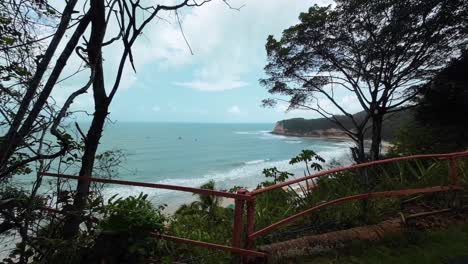 Tilt-up-shot-revealing-the-stunning-tropical-famous-tourist-destination-Madeiro-Beach-in-Pipa,-Brazil-in-the-state-of-Rio-Grande-do-Norte-surrounded-by-cliffs-with-small-waves-perfect-for-surfing