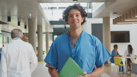 Retrato-De-Un-Médico-Masculino-Vistiendo-Batas-Sosteniendo-Notas-De-Pacientes-En-Un-Concurrido-Edificio-Del-Hospital