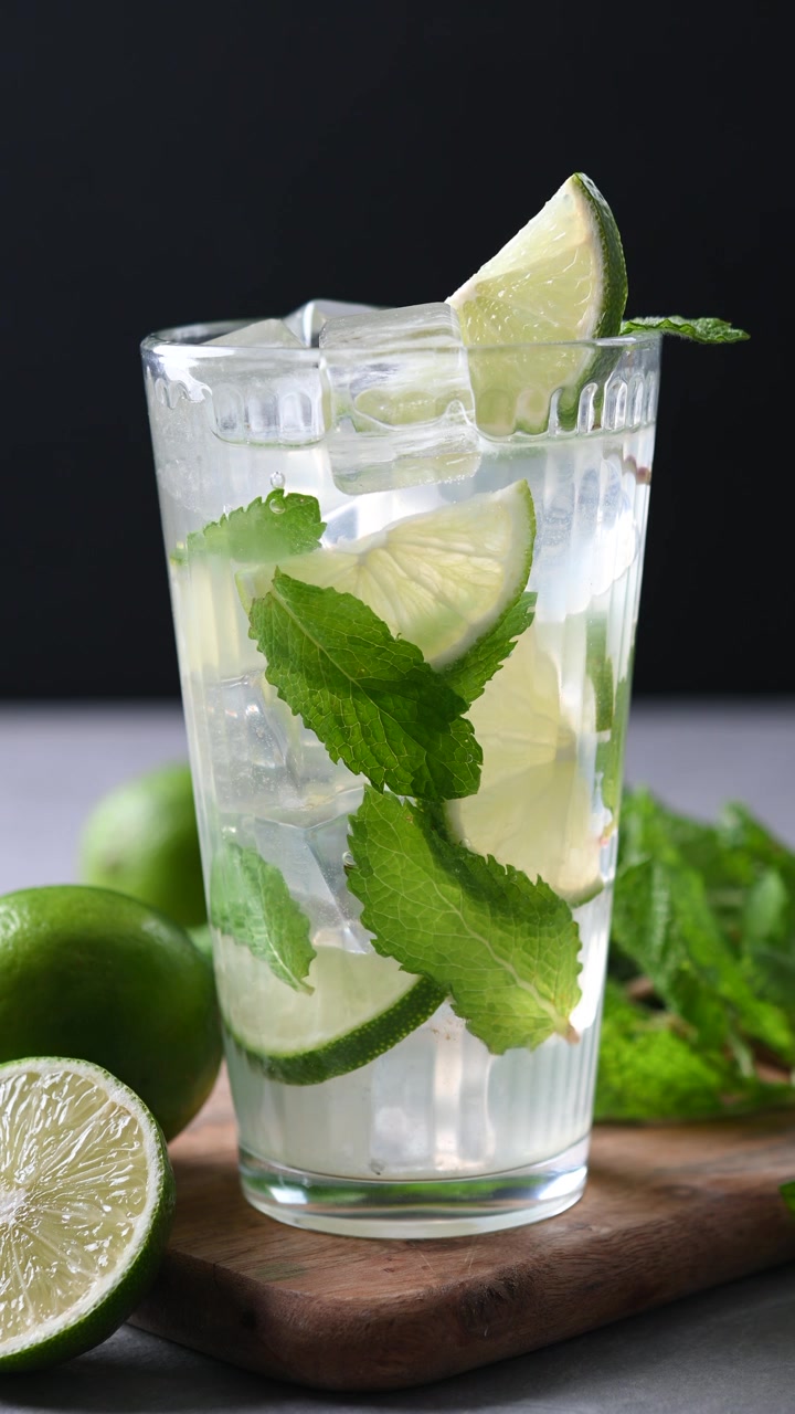 Limelohkon asettaminen mojito-cocktail-lasiin tuoreen mintun kera