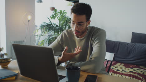young man video calling on laptop in home office
