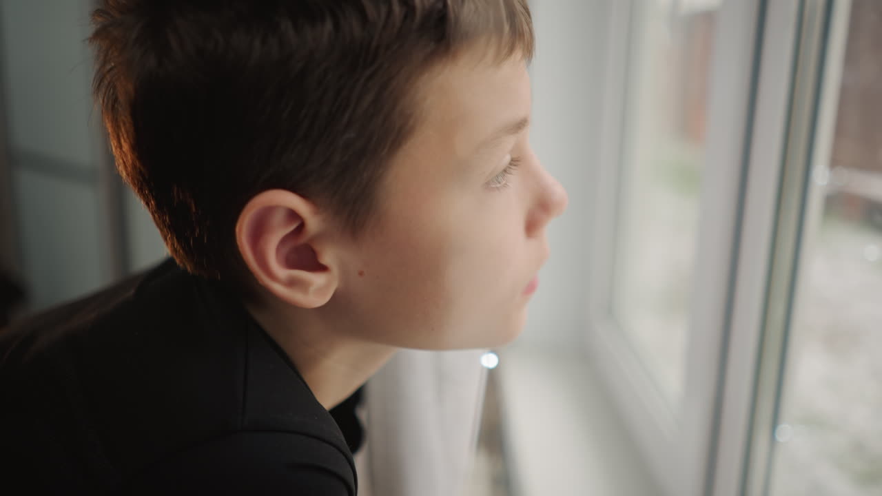 Pensive young observer. Boy contemplates on frosty winter day. Thoughtful youth gazes out on chilly winter morning scene. Young boy with serious look reflects quietly as winter morning begins
