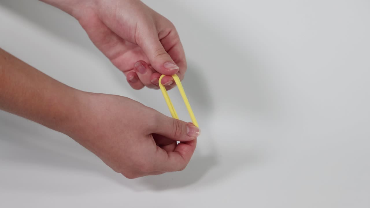 Hands manipulating a yellow hair tie