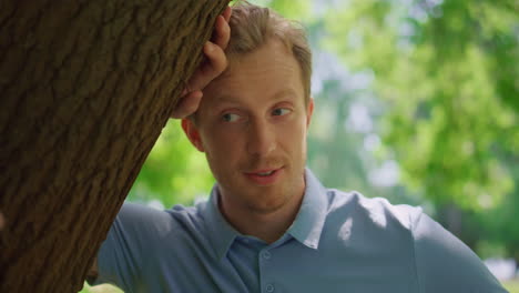 Closeup-attractive-man-talking-with-woman-lean-on-tree.-Young-male-stand-on-lawn