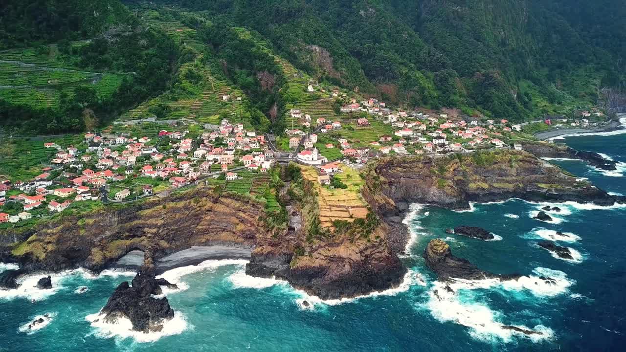 Breathtaking view of Seixal, Madeira, with its charming coastal village, red-roofed homes, steep green cliffs, terraced farmland, and the vibrant Atlantic Ocean, blending nature and tranquility