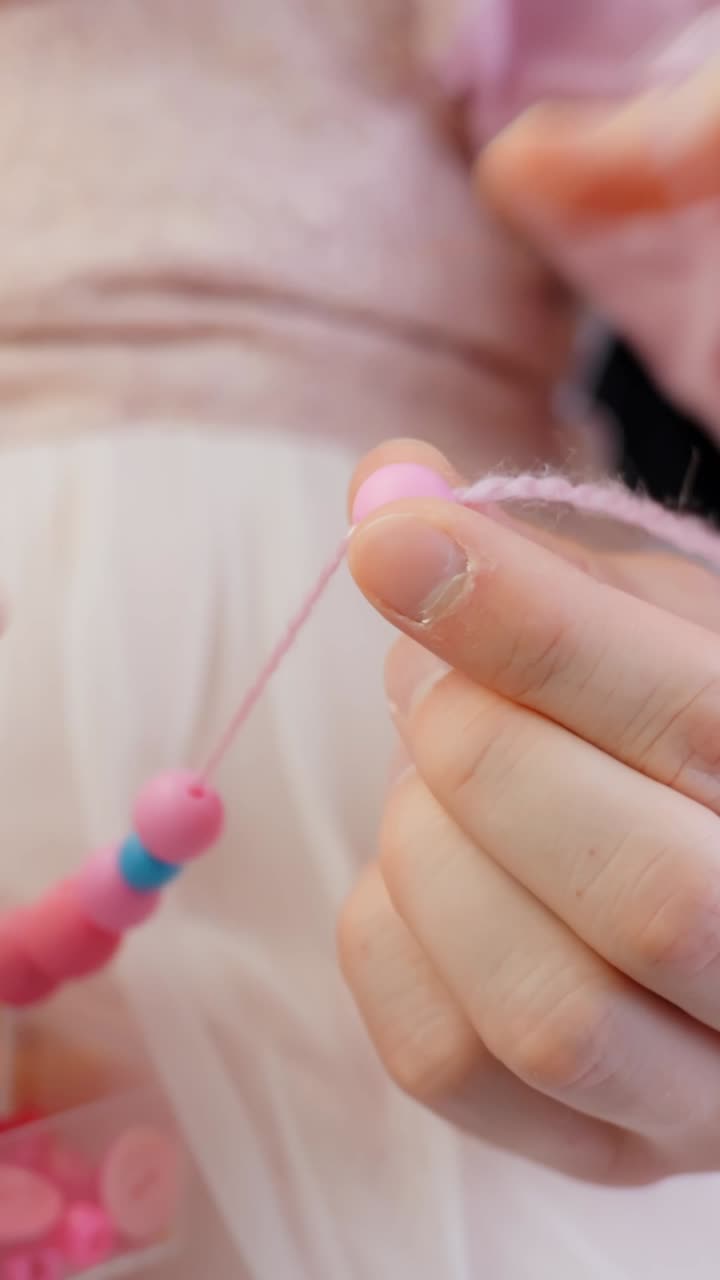 Family time together - making bead necklace, vertical close up view