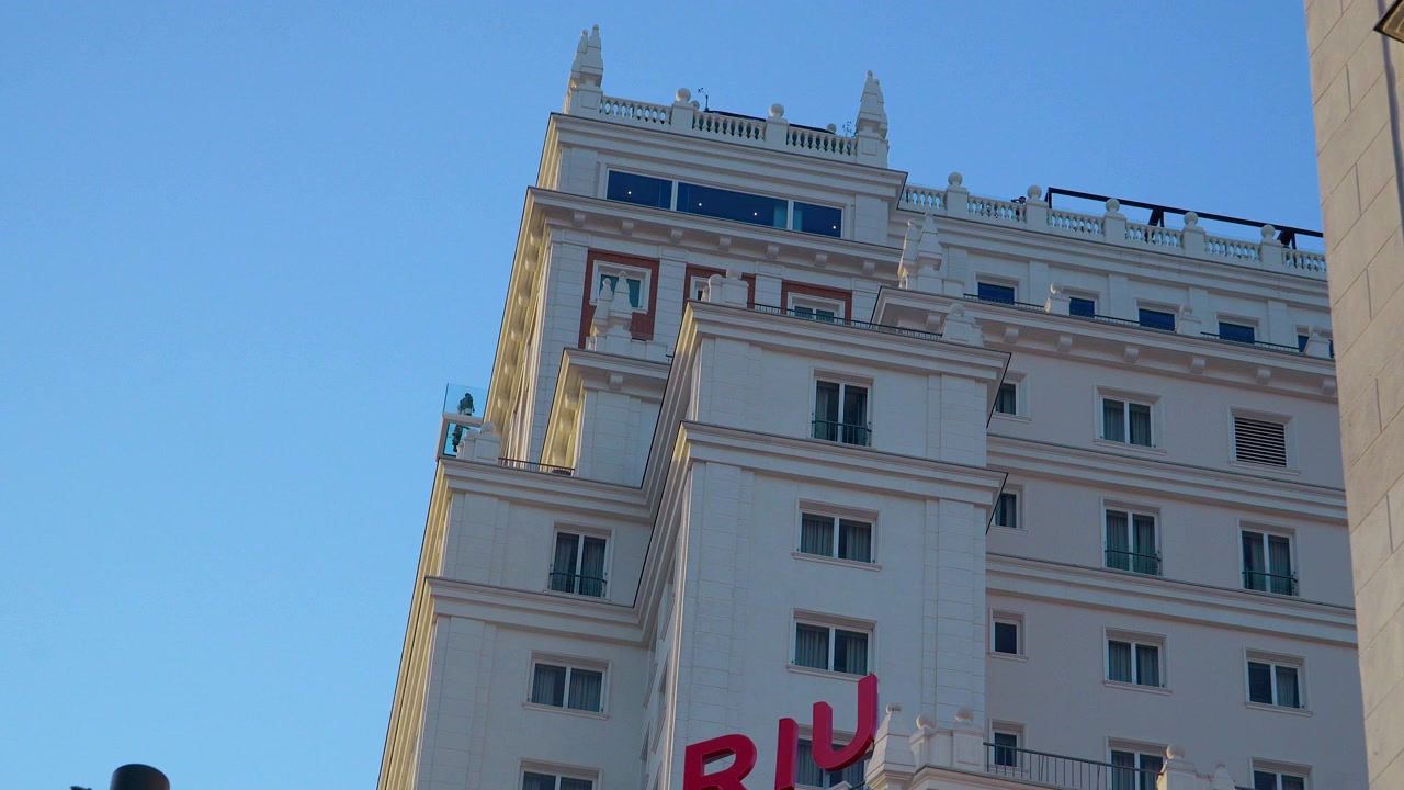 Toma de ángulo bajo del histórico rascacielos Riu Plaza España contra un cielo azul claro en Madrid, España. Adecuado para documentales de viajes y proyectos de arquitectura urbana.