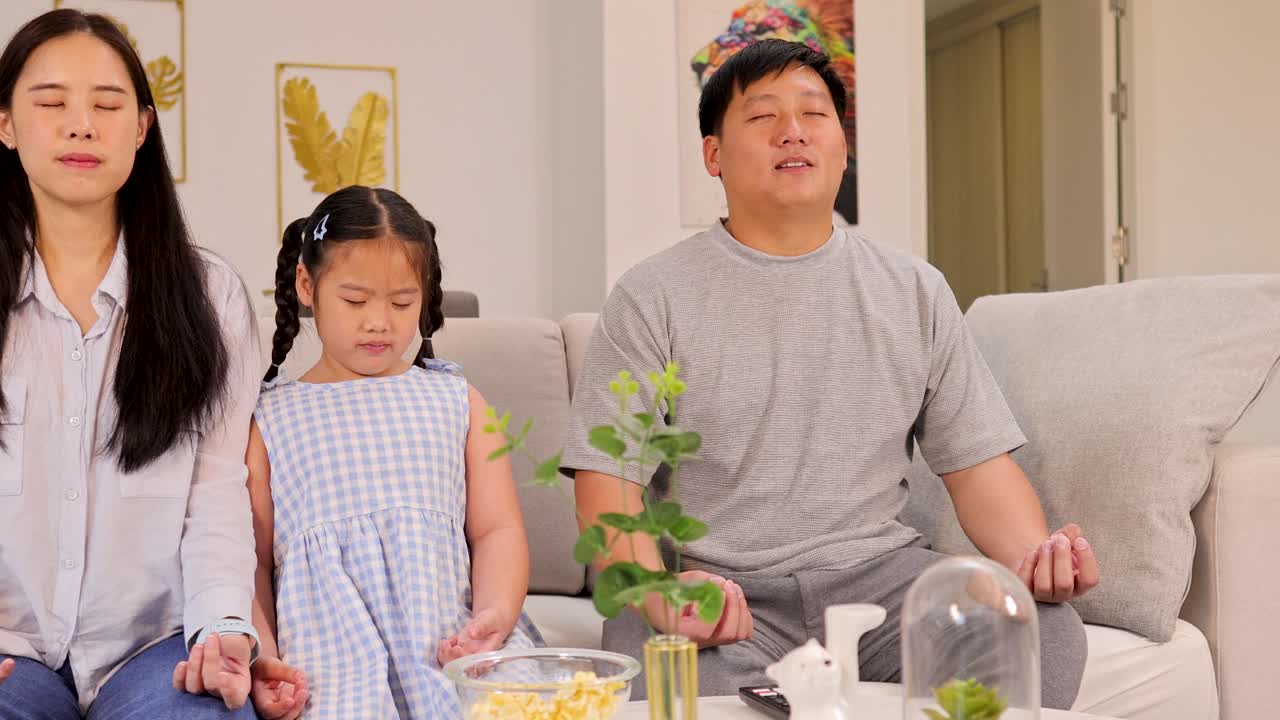 A family meditates on a sofa in a serene living room, conveying calmness and unity