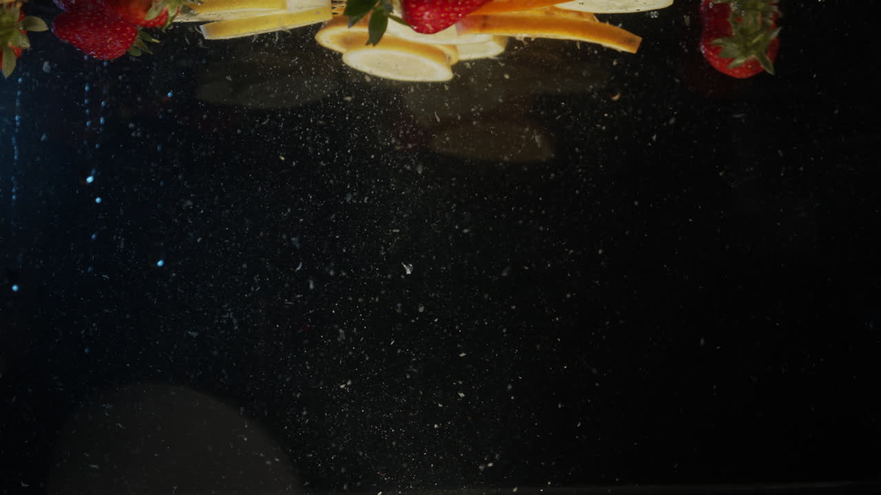 Lemon and orange slices strawberrys fruit falling into water slow motion