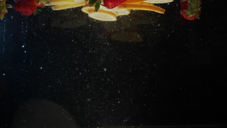 lemon and orange slices strawberrys fruit falling into water slow motion
