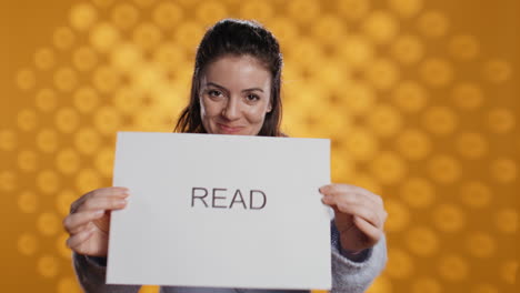 Woman-holding-message-in-hands-urging-people-to-read-more,-studio-background