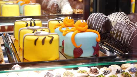 a display of delicious cakes in a bakery, including minion and octopus cakes