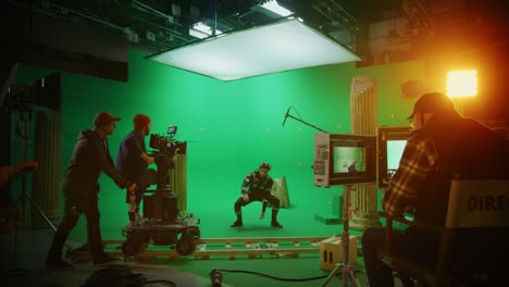 in the big film studio professional crew shooting blockbuster movie. director commands camera operator to start shooting green screen cgi scene with actor wearing motion tracking suit and head rig