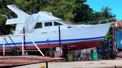 close-up of a yacht raised for hull maintenance in a tropical boat yard—great for marine repair, industry, or coastal infrastructure themes
