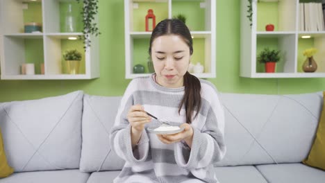 Healthy-young-beautiful-asian-young-woman-eating-yogurt-at-home.