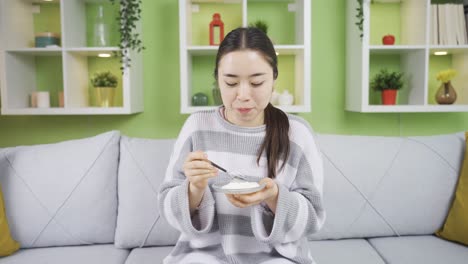 healthy young beautiful asian young woman eating yogurt at home.