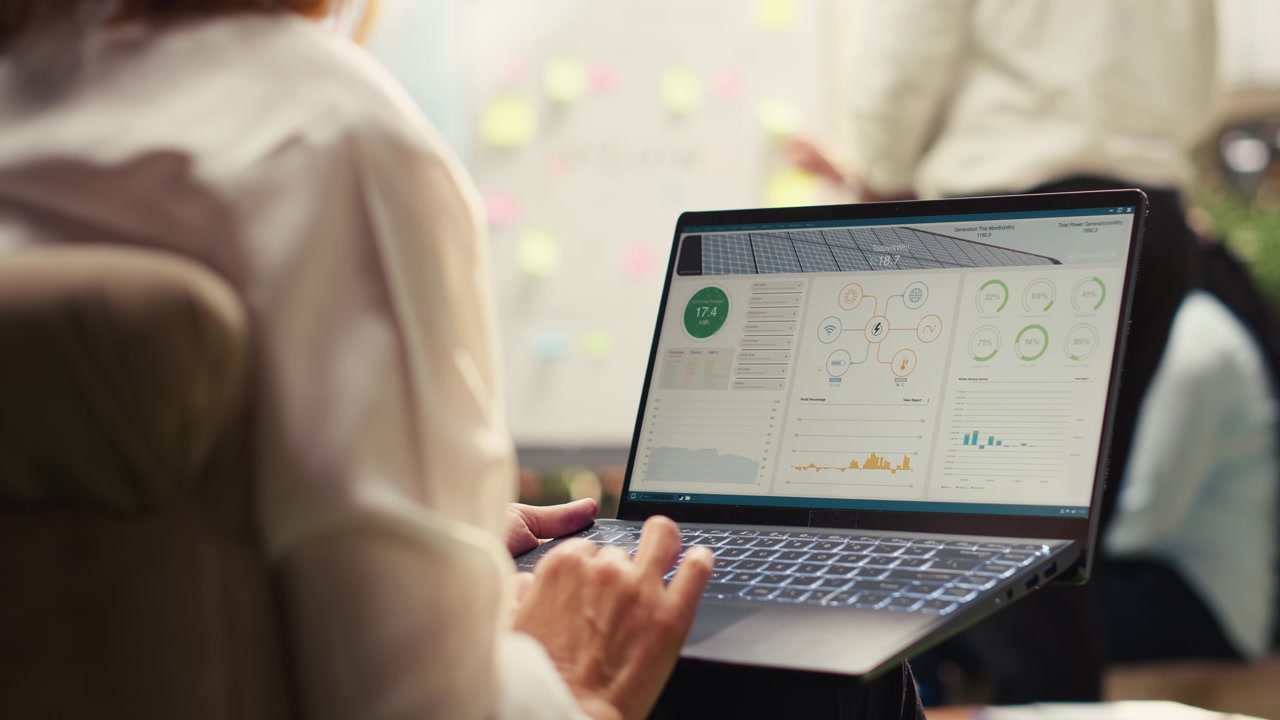 Business Professional Analyzing Solar Energy Data on Laptop in Office