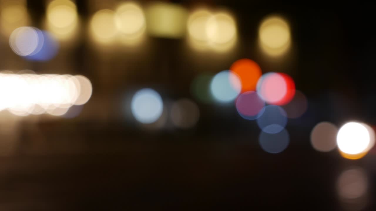 밤에는 어두운 흐릿한 배경에서 아름다운 반이는 보케, 둥근 다채로운 보케는 시내 거리에서 자동차 불빛에서 빛나고, 흐릿한 시내 불빛으로 초점을 맞추지 않습니다.