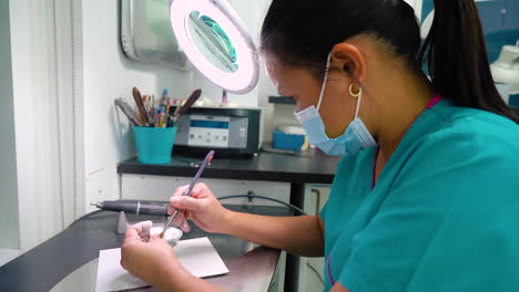 static shot of dental technician cleaning a tooth crown in the laboratory