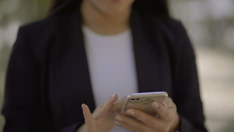 foto recortada de una mujer usando un teléfono inteligente al aire libre