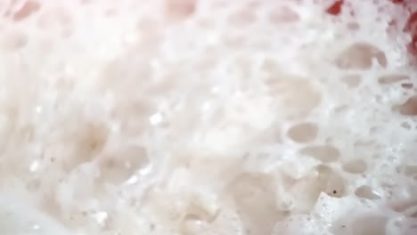 espuma de leche en una taza de chai, siendo eliminada con una cuchara