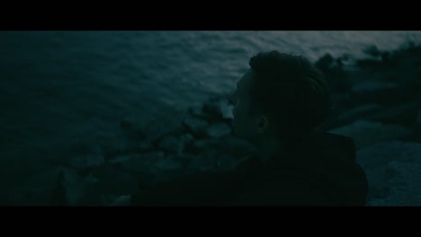 man smoking by the ocean at night