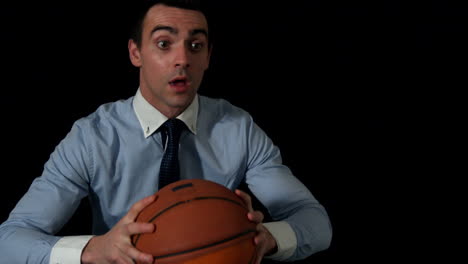 businessman throwing basketball to camera on black background