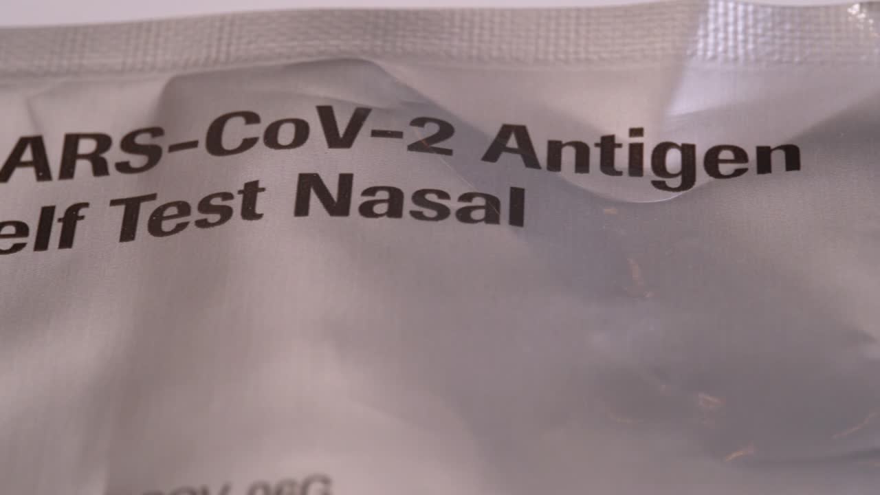 사스 코비드 홈 테스트 장비가 있는 멸균 백의 매크로 확대 - 슬라이더가 오른쪽에서 왼쪽으로 이동하여 가방 위에 텍스트 표시