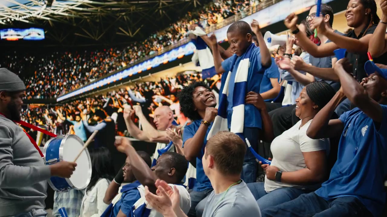 Diversos aficionados de fútbol del equipo azul coreando en las gradas abarrotadas del estadio.