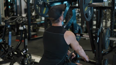 young sporty man using low row machine in gym