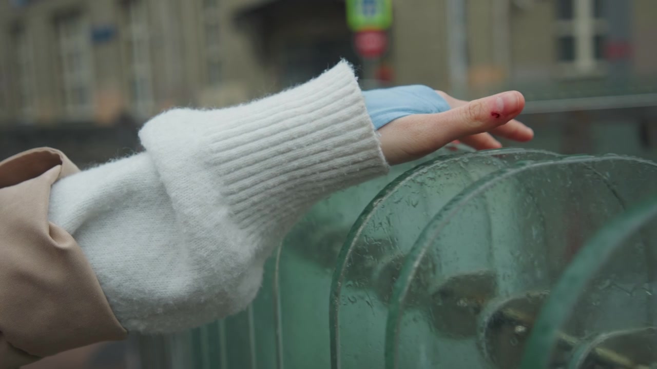 Close up of person hand with visible injury and bandage resting on glass surface. Hand remains steady showing texture details like fabric material in sleeve and water droplets on transparent