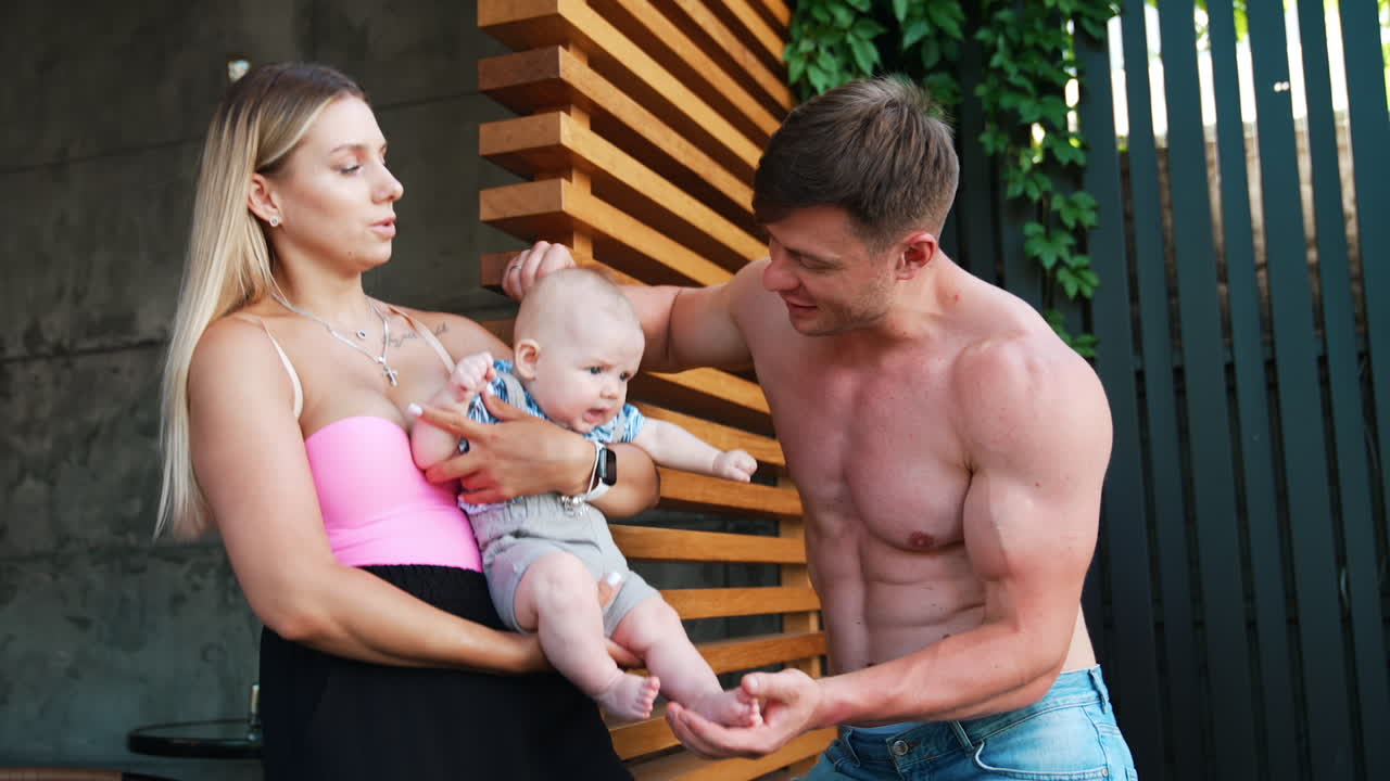 Caucasian couple with their infant outdoors. Family of three resting together in summer.