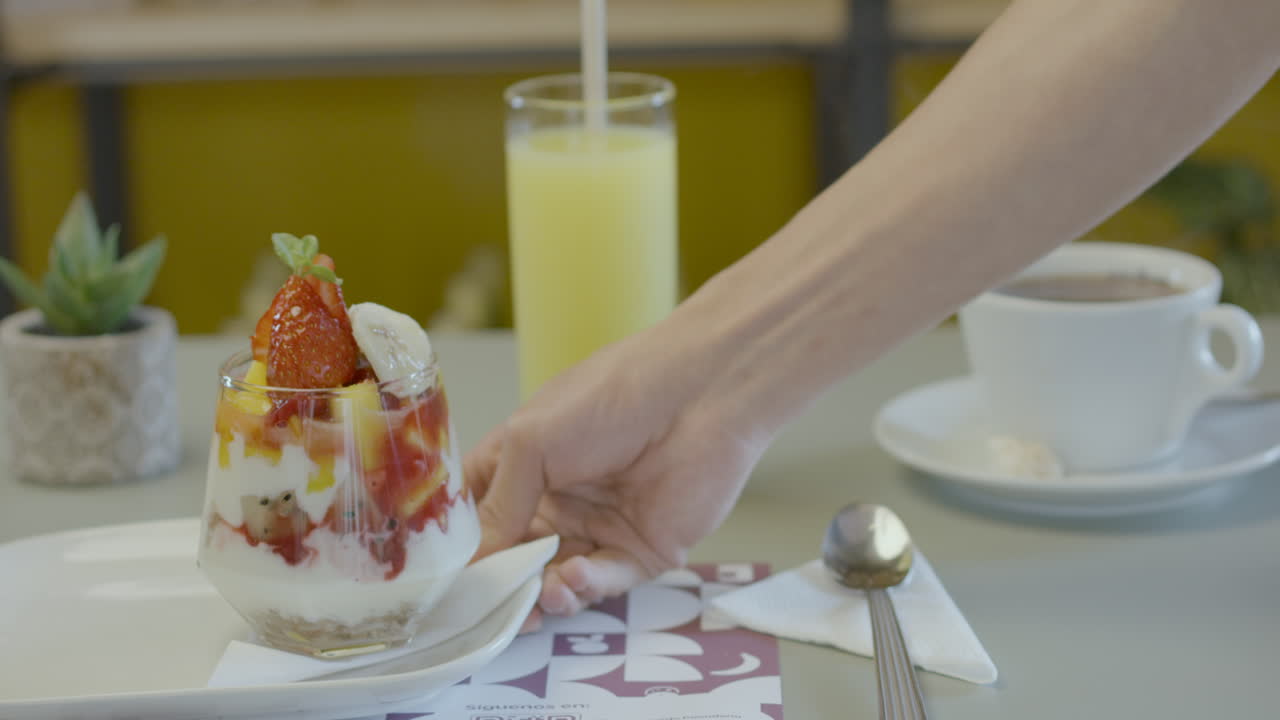 Close-up of a fresh breakfast consisting of a fruit salad with yogurt, a glass of juice, and a cup of hot coffee