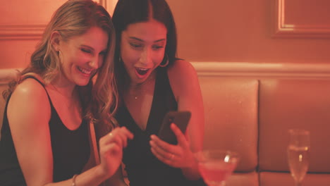 two young women using a smartphone together