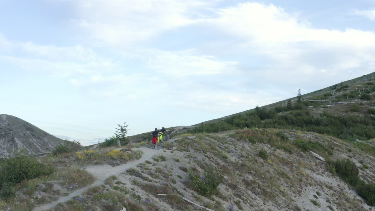 dos amigos con bicicletas de montaña caminando cuesta arriba en el sendero de la cresta de la montaña, monte st