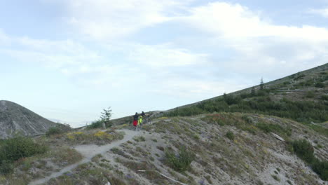 two friends with mountainbikes walking uphill on mountain ridge trail, mount st