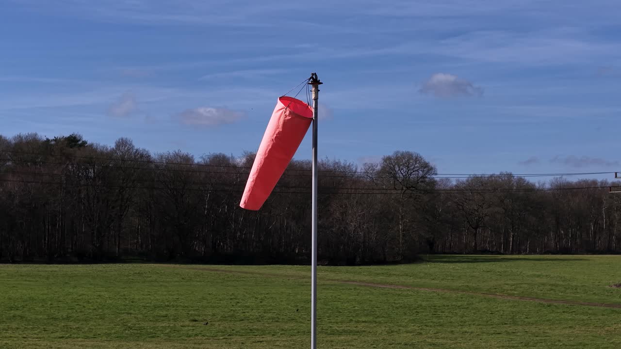 Red windsock blowing in the wind on a clear day in an open field