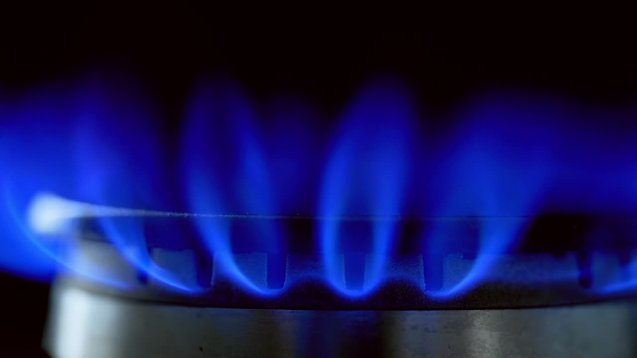 Gas blue flame. Gas stove on black background. Burning natural gas. Switching on fire on stove. Close-up.