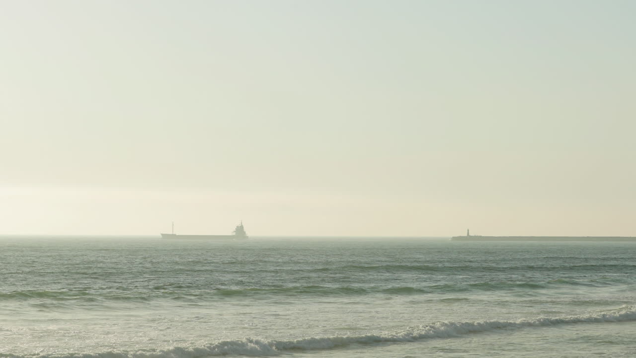 포르투갈 피게이라 다 포스의 해변 해안으로 파도가 몰아치는 안개 낀 바다를 순항하는 화물선