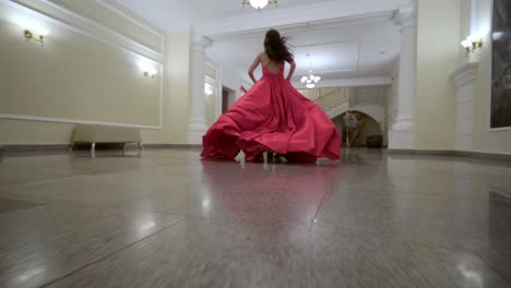 woman in a red dress running through a grand hall